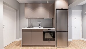 A modern kitchen with a built-in oven, a stainless steel refrigerator, and a double sink. - Waou Essence I Salamanca - Short-Term (Madrid)