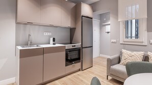 A modern kitchen with built-in appliances, a dining area with a table and chairs, and a window with blinds. - Waou Essence I Salamanca - Short-Term (Madrid)