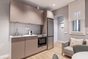 A modern kitchen with built-in appliances, a dining area with a table and chairs, and a window with blinds. - Waou Essence I Salamanca - Short-Term (Madrid)