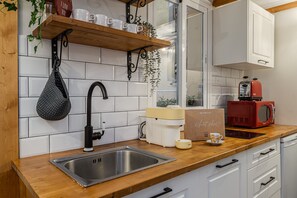 Eine Küche mit Spüle aus Edelstahl, einer roten Nespresso-Maschine und einer Holzausziehtafel.
