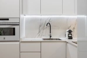 A modern kitchen with a built-in oven, a sink with a sleek faucet, and a coffee machine. - Waou Cuatro Caminos II - Short-Term Rental (Madrid)