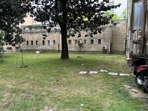 A courtyard with a tree, a building with multiple windows, and a parked motorcycle. - Venicenight Apartment 25 (Venezia)