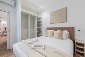 A bedroom with a bed, a bedside table, a wardrobe, and a painting on the wall. - Waou El Rastro II - Short-Term Rental (Madrid)