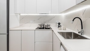 A modern kitchen with white cabinetry, a stainless steel sink, and a black faucet. - Waou El Rastro II - Short-Term Rental (Madrid)