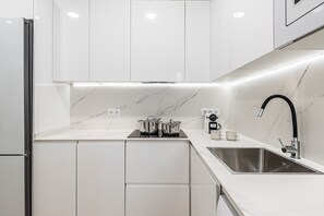 A modern kitchen with white cabinetry, a stainless steel sink, and a black faucet. - Waou El Rastro II - Short-Term Rental (Madrid)