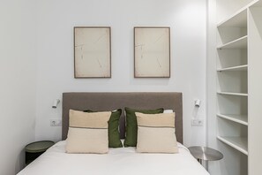 A bed with a headboard, two wall-mounted artworks, bedside lamps, and a small round table. - Waou El Rastro II - Short-Term Rental (Madrid)