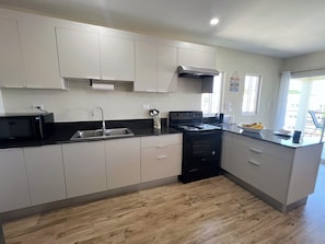 A modern kitchen with a stove, sink, and microwave.