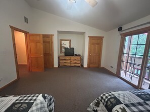A room with two beds, a dresser, a television, and a sliding glass door to a balcony.