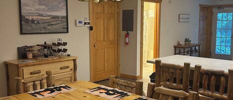 Un coin repas avec une table en bois, des chaises, un lustre et un ventilateur de plafond.