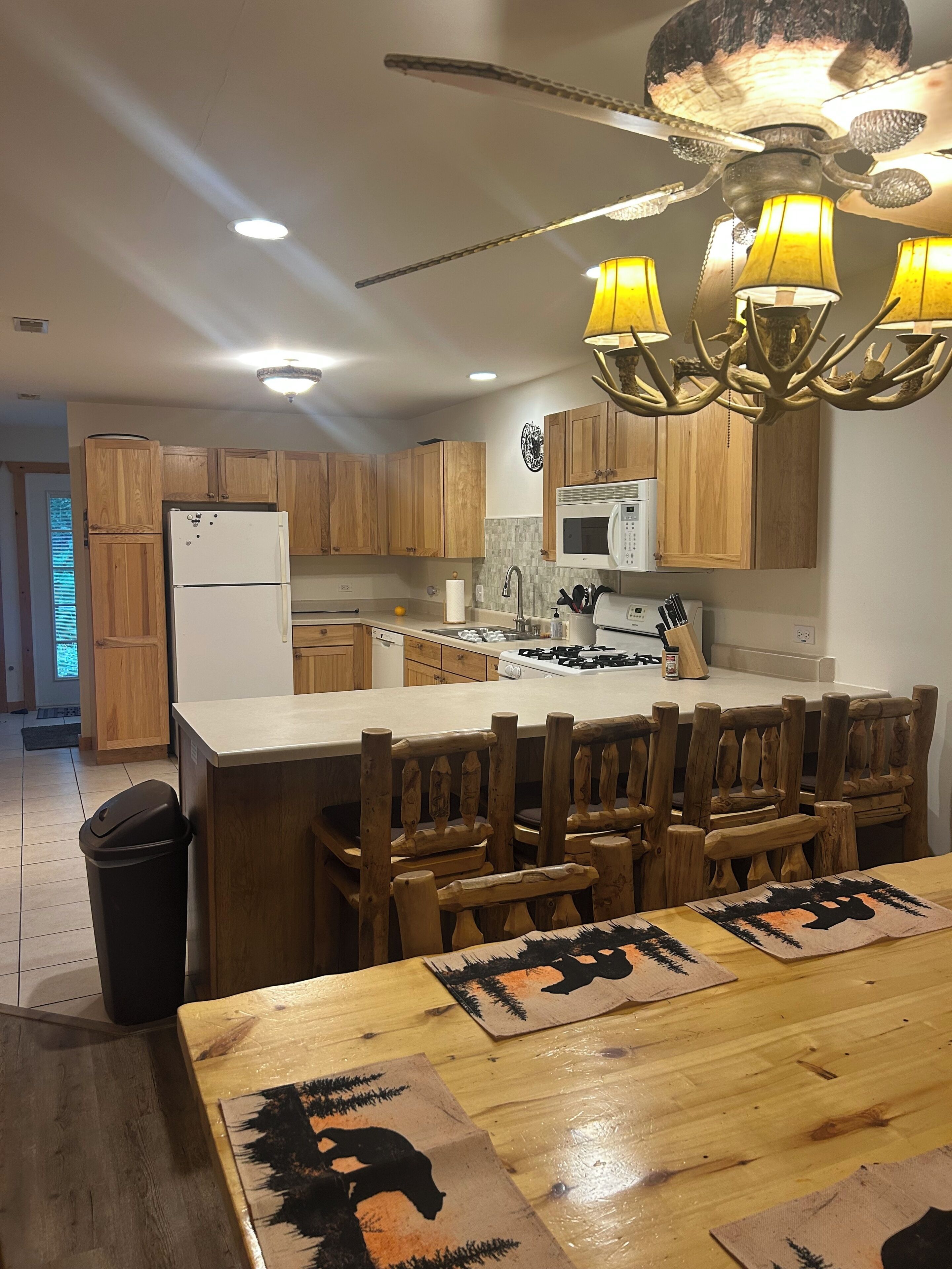 A kitchen with wooden cabinets, a central island, and a ceiling fan with lights.