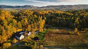Paisagem rural com uma casa rodeada por árvores e campos.