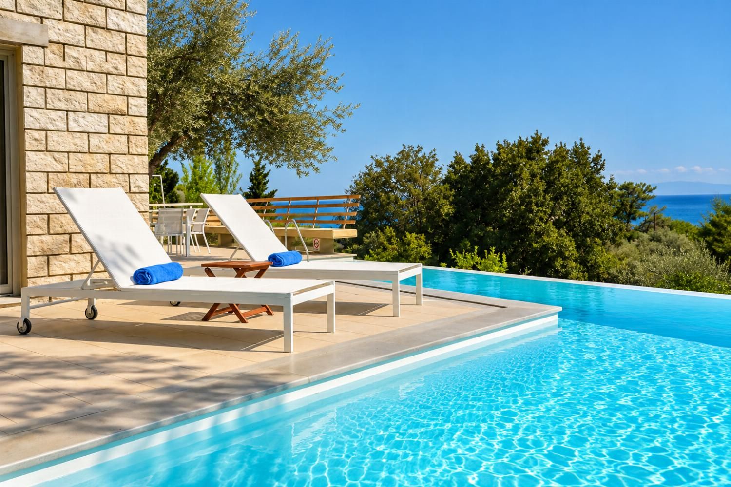 A poolside area with lounge chairs and a view of the sea.