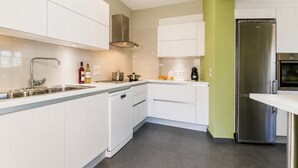 A modern kitchen with white cabinets, stainless steel appliances, and a green accent wall. - Villa Oleana - Three Bedroom Villa, Sleeps 6 (Lefkada City)