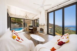 A modern living room with a pool, a dining area, and a fireplace. - Pomos View Villa - Four Bedroom Villa, Sleeps 8 (Pomos)