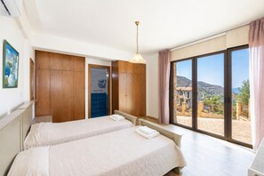 Quarto de hotel com duas camas, uma janela grande e vista para o exterior.
