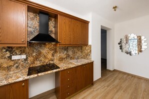 A kitchen with wooden cabinets, a granite countertop, a black range hood, and a wall-mounted mirror. - Pomos View Villa - Four Bedroom Villa, Sleeps 8 (Pomos)