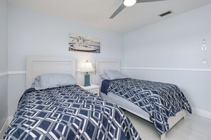 A bedroom with two beds, a ceiling fan, a wall-mounted light, and a painting. - Relaxing 3BR Lakehouse with Heated Pool & Lake Views (Port Charlotte)