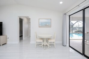 Ein modernes Interieur mit Essbereich, einem Gemälde und Blick auf einen Pool.