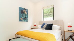 A modern bedroom with a bed, bedside tables, a bench, and a window. - Villa LaLa Land • 13 Suites • 2 Pools • Party Room (Jaco)
