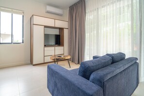 A modern living room with a sofa, a television, and a wardrobe. - Villa LaLa Land • 13 Suites • 2 Pools • Party Room (Jaco)