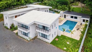 A modern two-story building with a swimming pool, surrounded by greenery. - Villa LaLa Land • 13 Suites • 2 Pools • Party Room (Jaco)