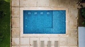 A rectangular swimming pool with a tiled edge, surrounded by stone paving, and a small drainage channel at the bottom. - Villa LaLa Land • 13 Suites • 2 Pools • Party Room (Jaco)