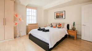 A bedroom with a bed, a wardrobe, a bedside table, a nightstand, a window, and a framed picture on the wall. - Cosy One-Double room flat near Big Ben (London)