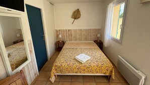 Een slaapkamer met een bed, twee nachtkastjes, een raam, een radiator en een spiegel.