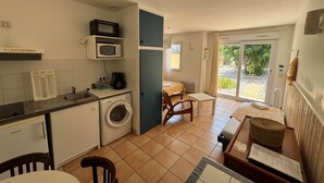 Een kleine keuken met een wasmachine, magnetron en koffiezetapparaat.