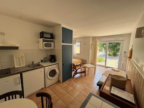 A compact kitchen with a washing machine, microwave, and coffee maker. - Jonquille Studio - Le Patio Residence (Mimizan)