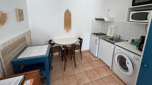 Een kleine keuken met een eethoek, een wasmachine en een magnetron.