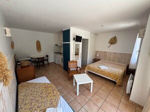 A room with a bed, a desk, a chair, a washing machine, and a television. - Jonquille Studio - Le Patio Residence (Mimizan)