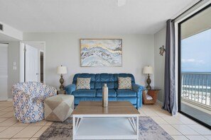 Un salon avec un canapé bleu, un fauteuil à motifs et une table basse.