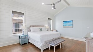 Ein Schlafzimmer mit Bett, Nachttischen, einer Bank, einem Deckenventilator und einem Bild an der Wand.