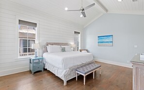 Ein Schlafzimmer mit Bett, Nachttischen, einer Bank, einem Deckenventilator und einem Bild an der Wand.