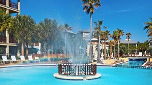 Ein Pool mit einer zentralen Fontäne, umgeben von Liegestühlen und Palmen.