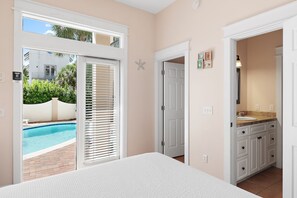A bedroom with a large window, a door leading to a bathroom, and a view of a swimming pool. - 🏖️ The Mermaid | Private Pool • 6 Bikes • Walk to Beach 🌊 (Inlet Beach)