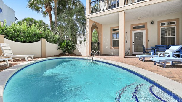 Ein Swimmingpool mit klarem, blauem Wasser, umgeben von Liegestühlen und einem Gebäude mit einem Balkon.