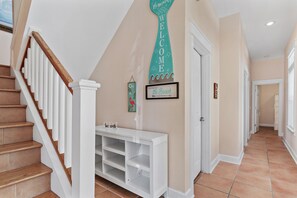A hallway with a staircase, a welcome sign, and a sign indicating a path to the beach. - 🏖️ The Mermaid | Private Pool • 6 Bikes • Walk to Beach 🌊 (Inlet Beach)