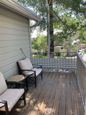A wooden deck with two chairs and a small table, surrounded by a metal railing. - Adorable 2-bedroom condo in Kings Beach with beach access. (Kings Beach)