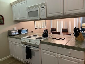A kitchen with white cabinets, a microwave, a toaster, a stove, and a kettle. - Adorable 2-bedroom condo in Kings Beach with beach access. (Kings Beach)