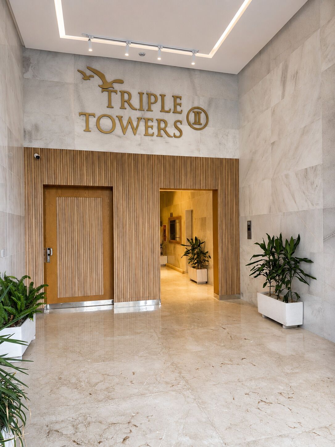 A hotel entrance with a sign reading 'TRIPLE TOWERS' and a modern interior design.
