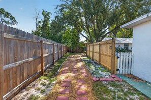 A narrow pathway with stepping stones leading to a white building, surrounded by wooden fences and greenery. - Brand new Cozy 1-bedroom building in charming Lake Placid with AC (Lake Placid)
