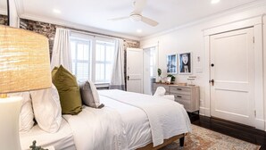 Ein Schlafzimmer mit Bett, Nachttisch, Lampe und Kommode mit Spiegel.