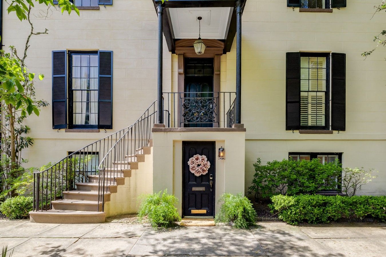 A two-story building with a black front door, a small porch with a railing, and a staircase leading to the entrance.