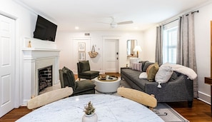 Ein Wohnzimmer mit Kamin, Fernseher, Sofa und Couchtisch.