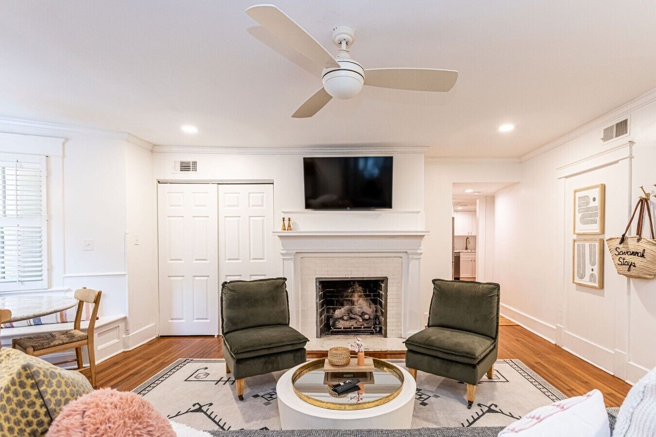 A living room with a fireplace, two armchairs, a coffee table, and a ceiling fan.