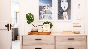 A hotel room with a wooden dresser, two framed pictures on the wall, a plant, and a small wooden box on the dresser.