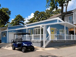 Ein blaues Gebäude mit einer überdachten Veranda und einem Golfwagen davor.