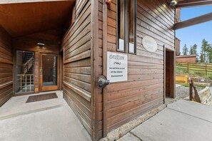 Un bâtiment en bois sur lequel est apposée une pancarte indiquant : « ATTENTION : la glace et la neige font partie du paysage alpin », et une porte marquée du mot « ENTRÉE ».
